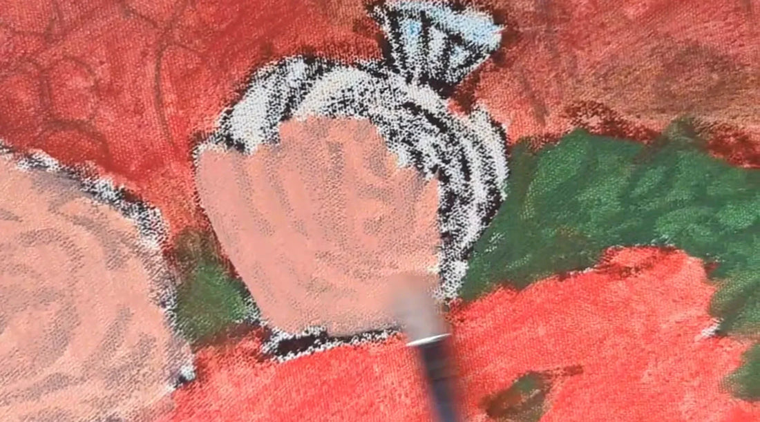 A paint brush covers the white of the canvas with a very thin pink oil paint that will take the shape of a flower.  Other colors on the canvas include red and green oil paint.